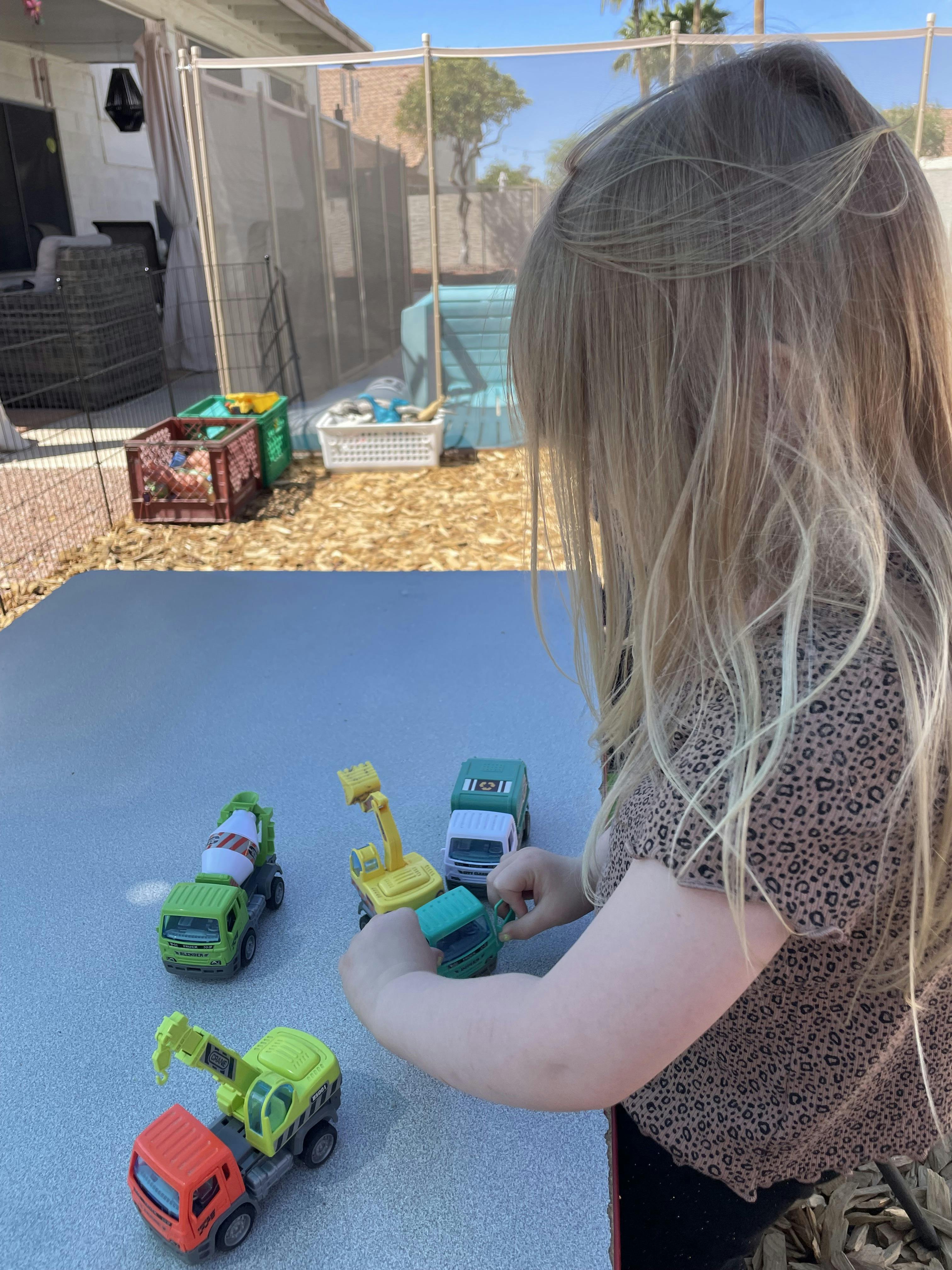 Child playing with toy construction vehicles on a table