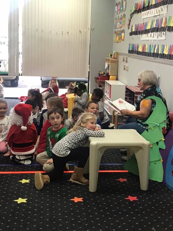 Adult reading to a group of children in a classroom