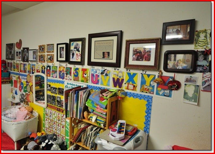 Wall with framed pictures, alphabet cards, and children's drawings