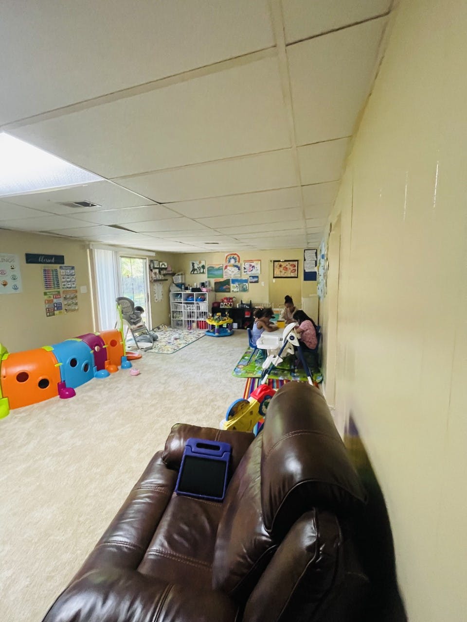 Children playing in a room with toys and a person sitting on a couch