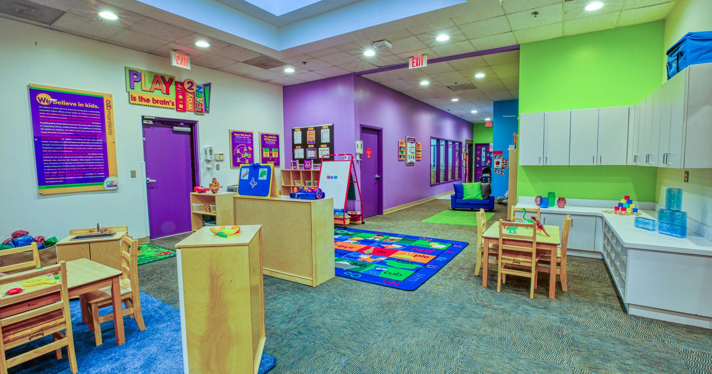 Colorful classroom with child-sized tables and chairs, play mats, and learning materials