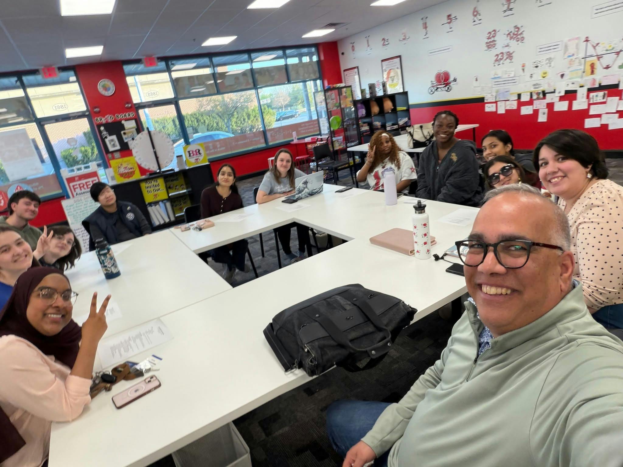 A diverse group of people sitting around a large white table in a classroom