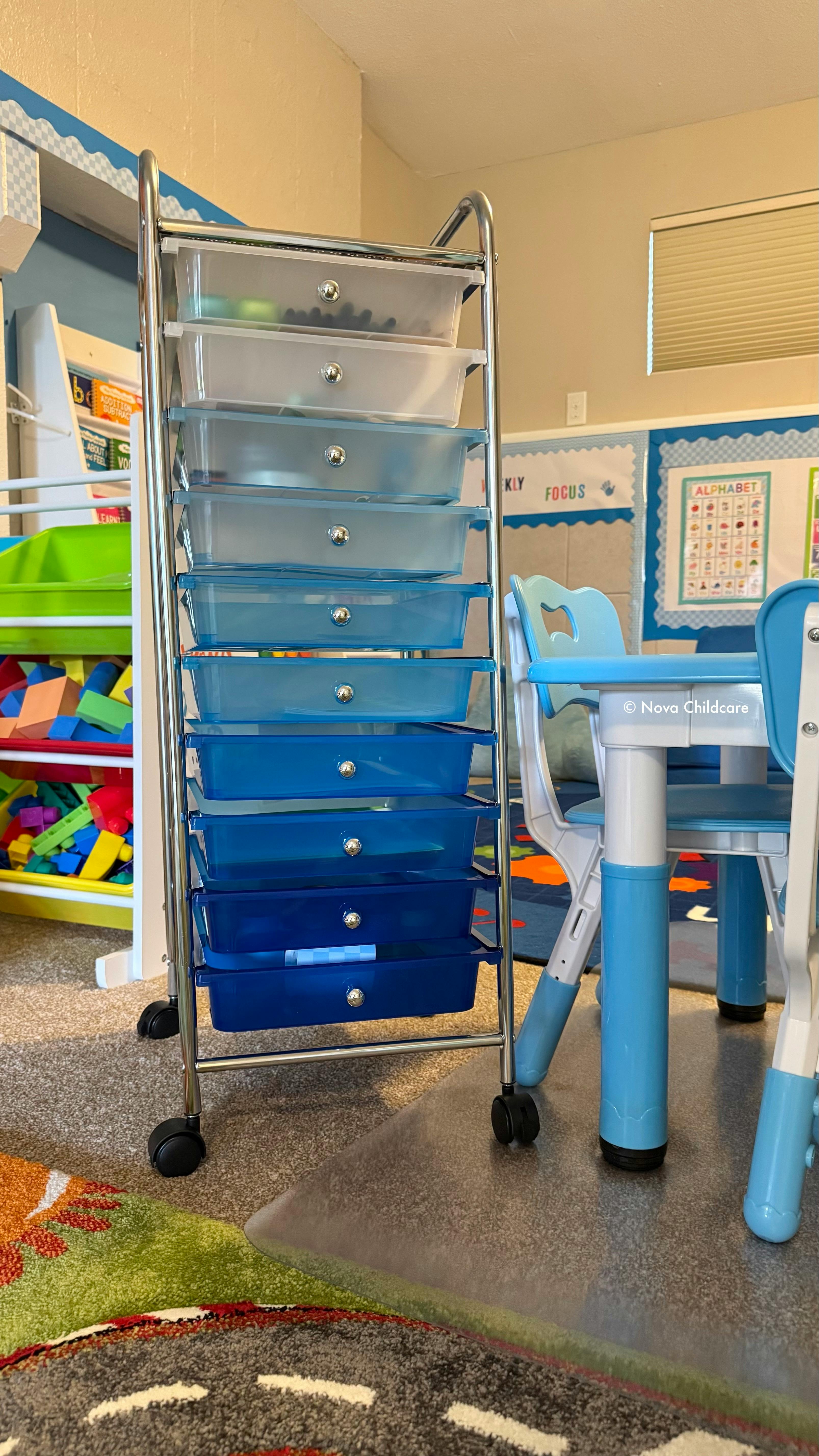 Rolling storage cart with clear and blue drawers in a classroom with a child's table and chairs