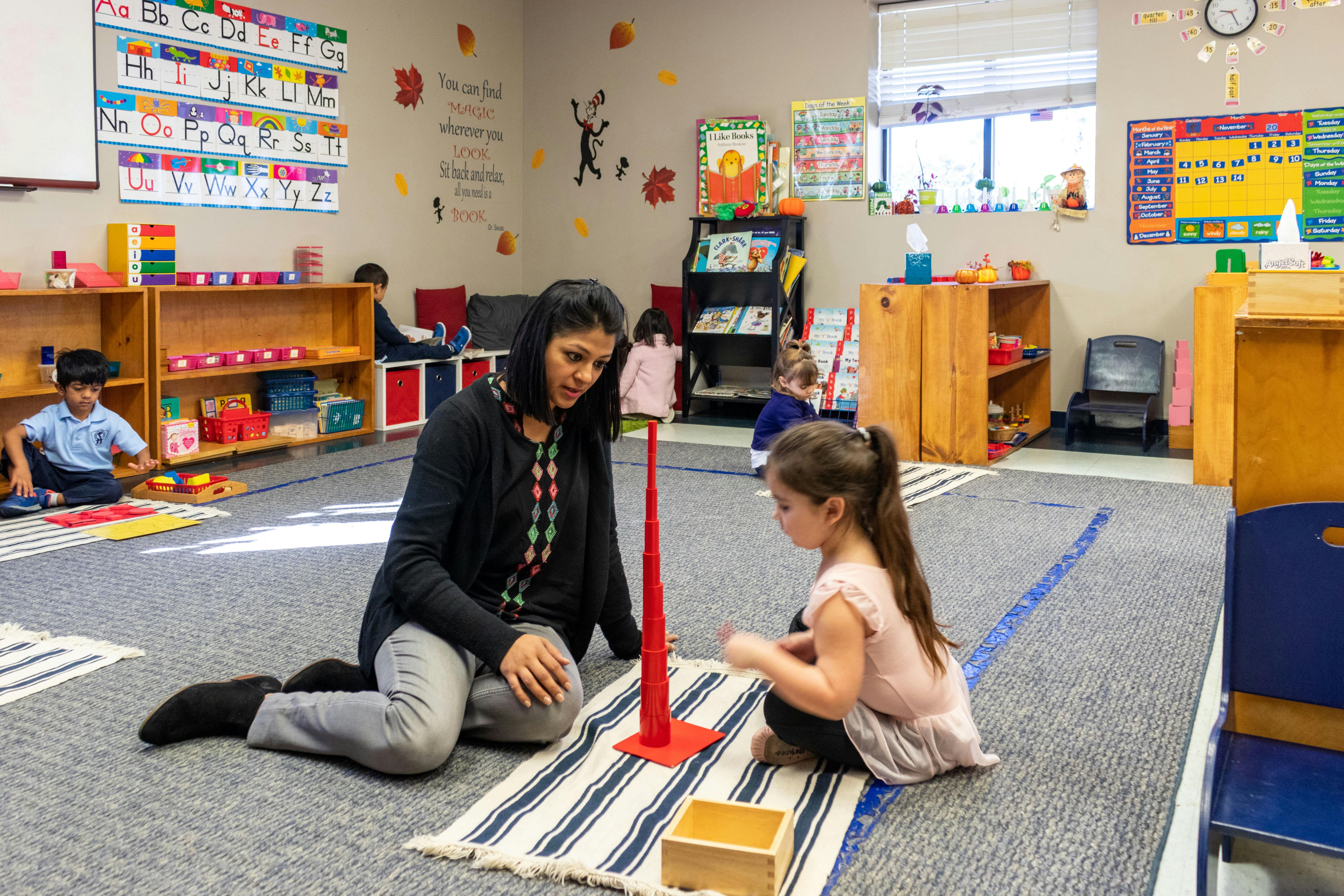 Adult and child on floor in classroom with red cone