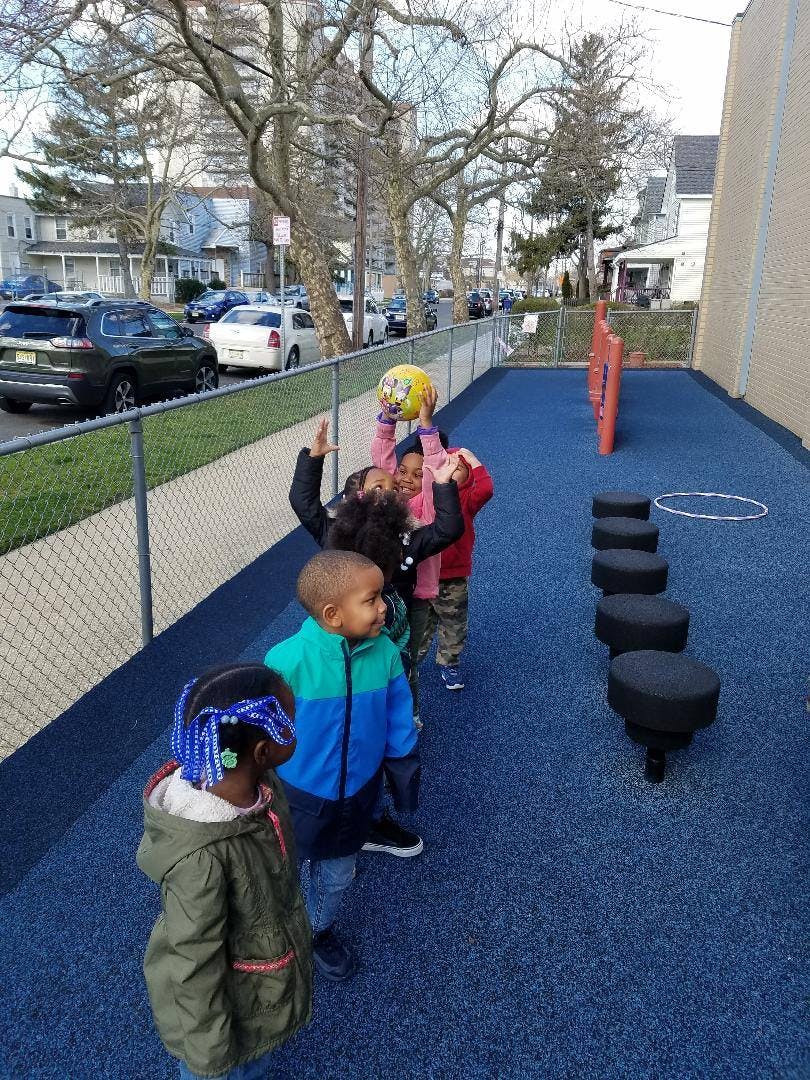 Children playing with a ball on a blue playground surface