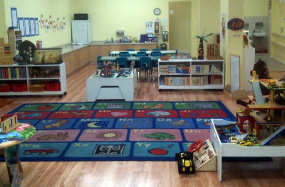 Playroom with colorful alphabet rug, tables, and shelves