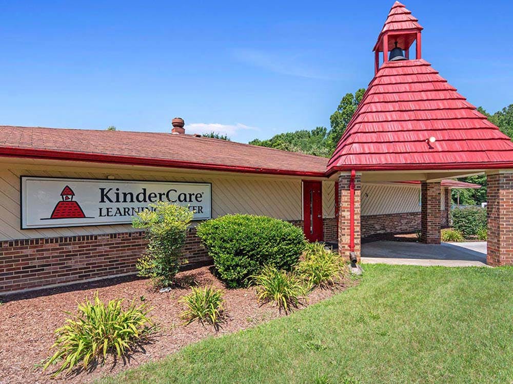 KinderCare Learning Center building with red roof, brick facade, and bell tower