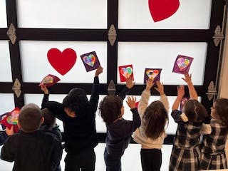 Children holding up heart-themed artwork