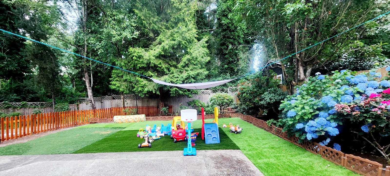 Outdoor play area with artificial turf, toys, and lush greenery