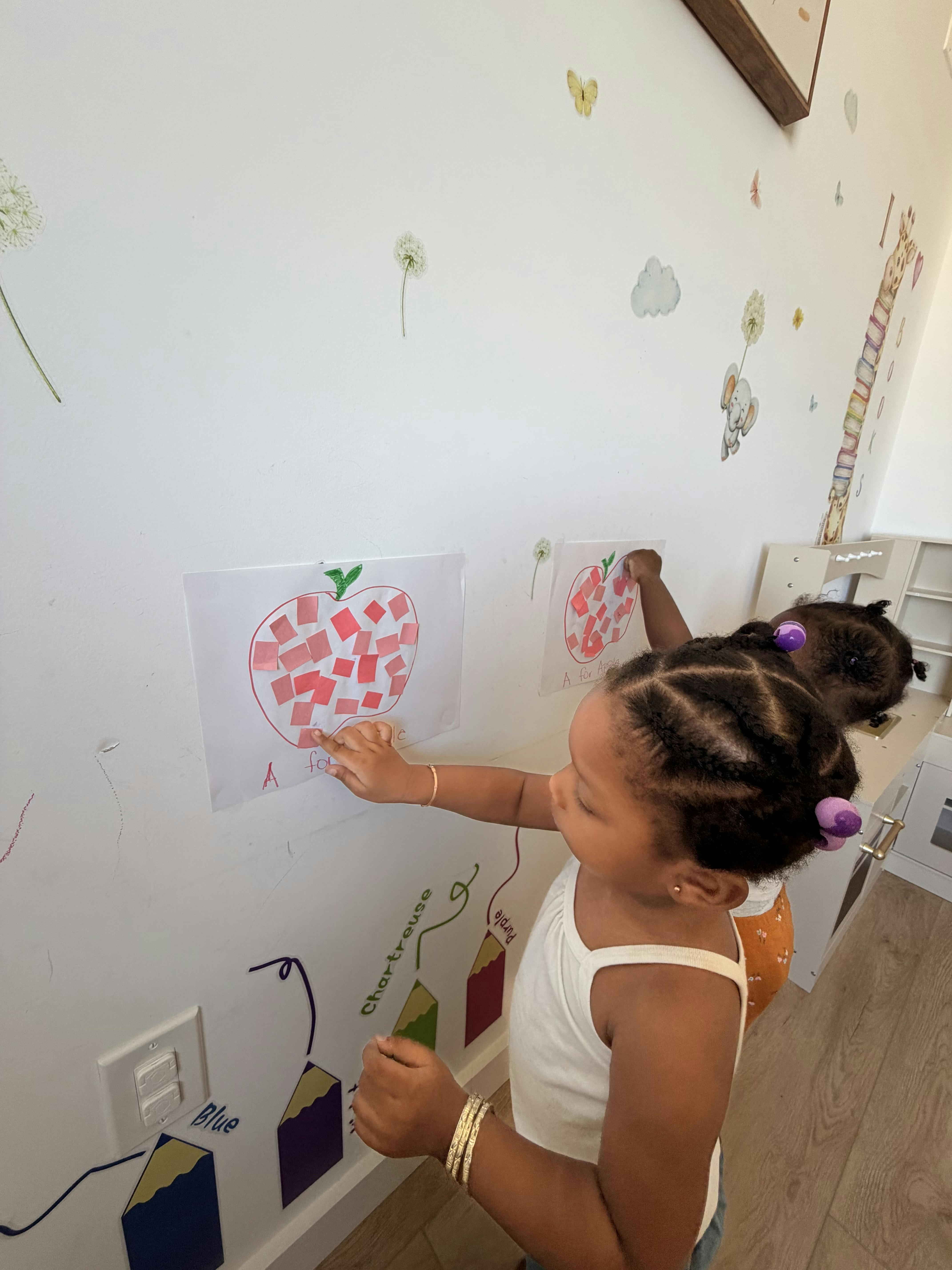 Child pointing at an apple drawing on a wall