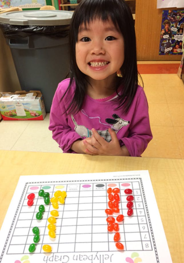 Child smiling at a table with a jellybean graph