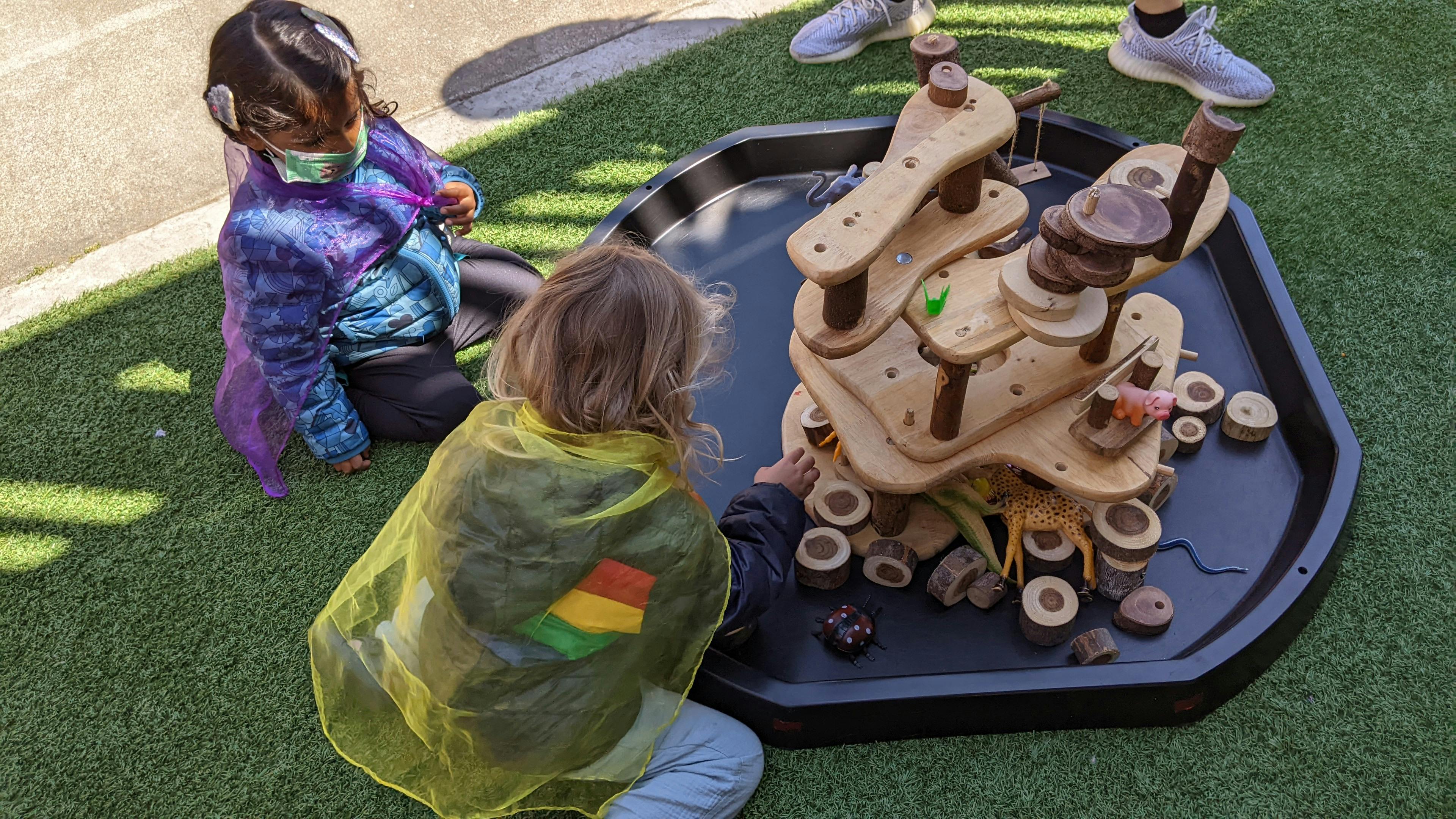 Two children playing with a wooden water table