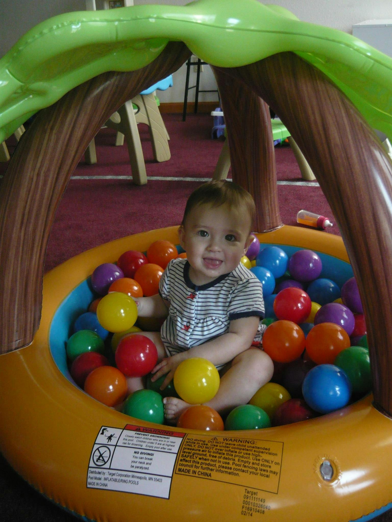 Child sitting in an inflatable ball pit