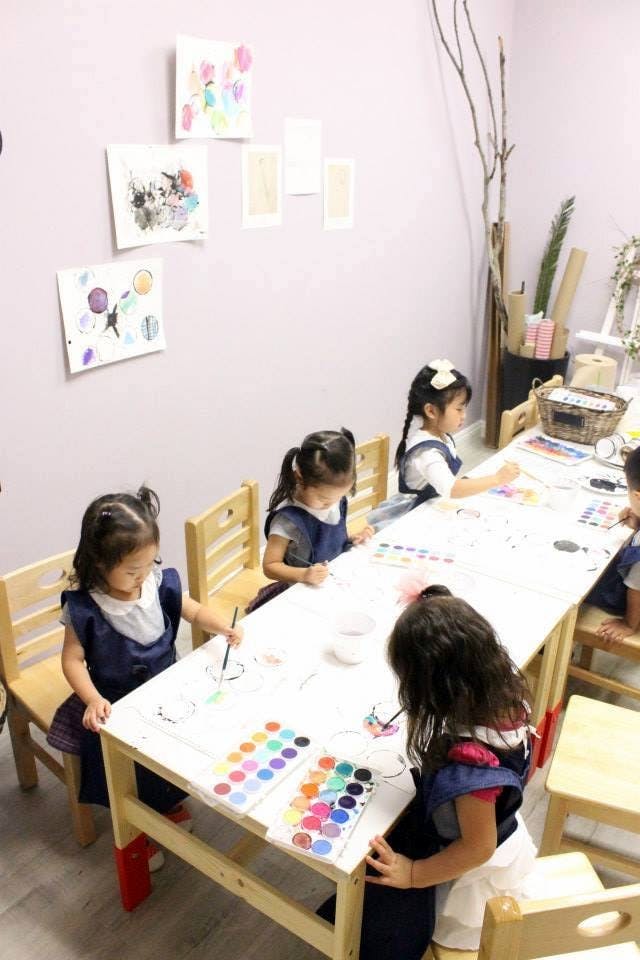 Children painting at a table in a classroom
