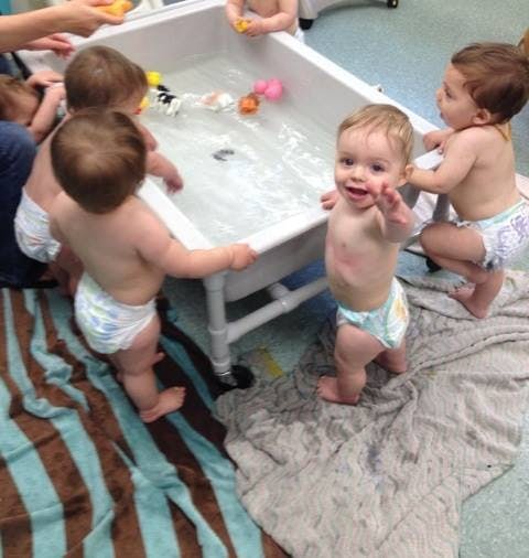 Multiple children playing with toys in a water table