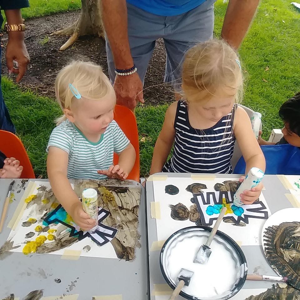 Two children painting at a table outdoors