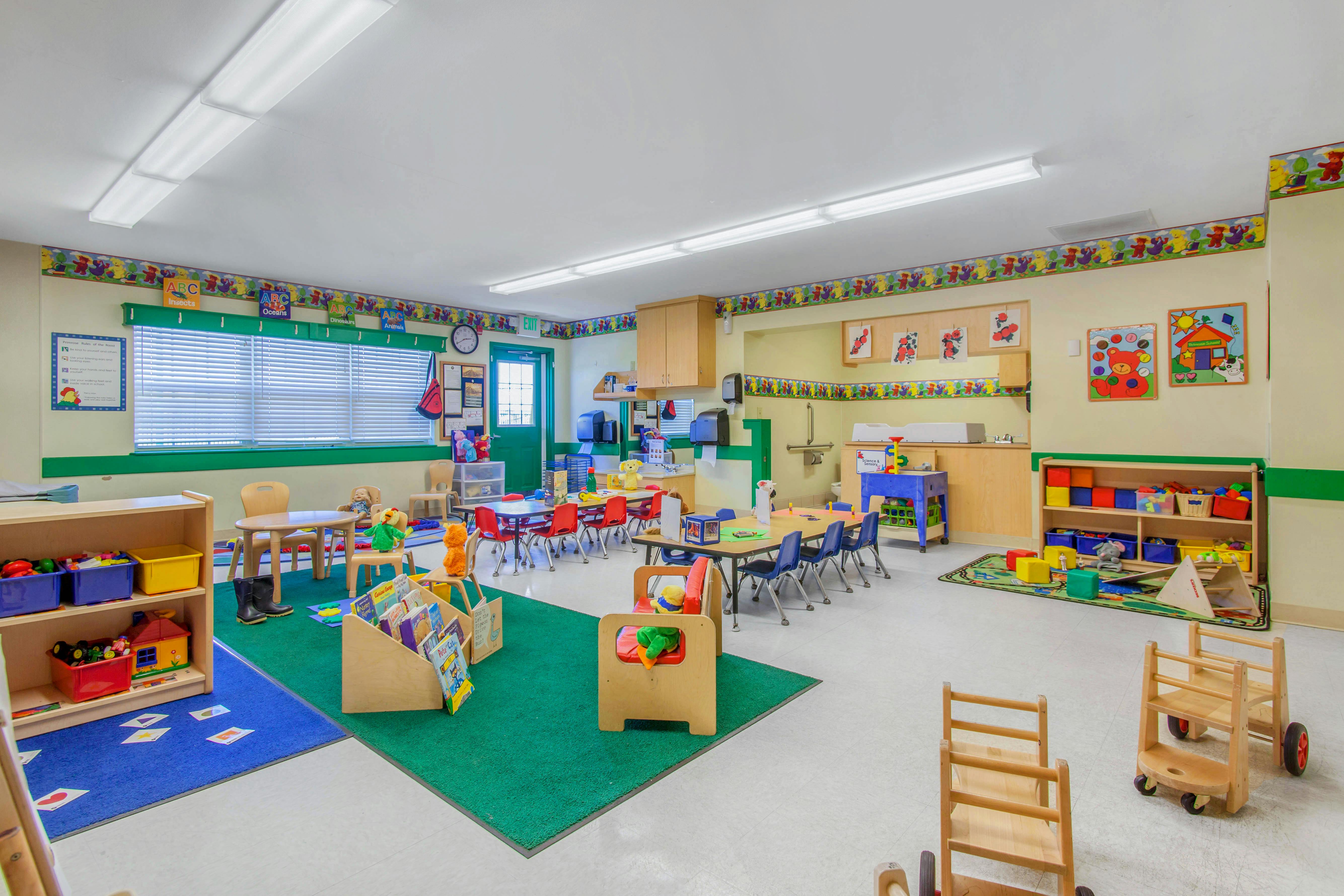 Colorful classroom with child-sized tables and chairs, shelves with toys