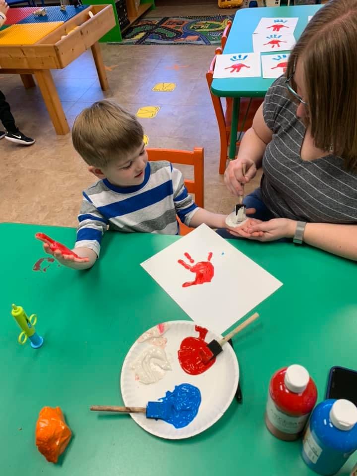 Child and person doing handprint painting