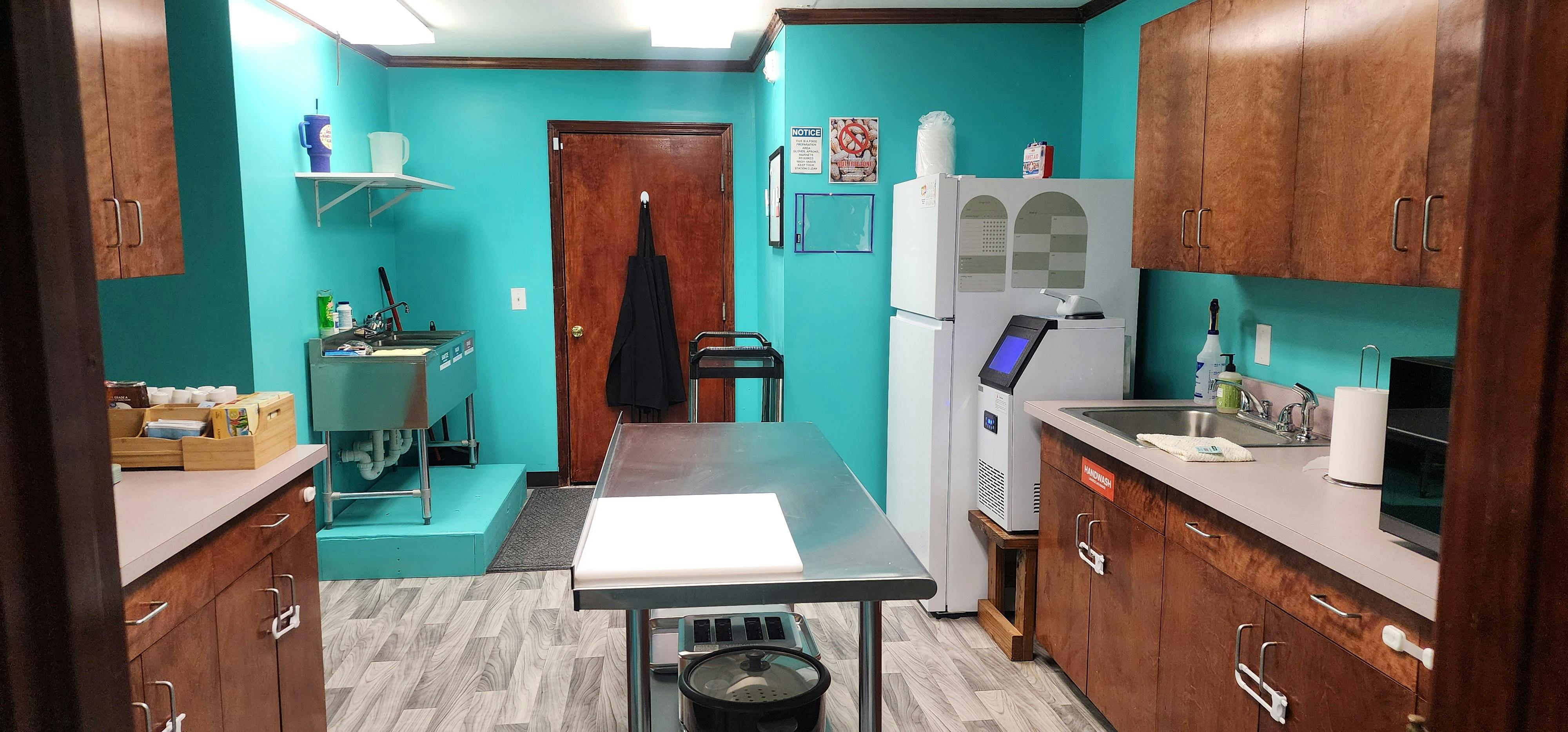 Kitchen area with turquoise walls, wood cabinets, stainless steel sink, and appliances