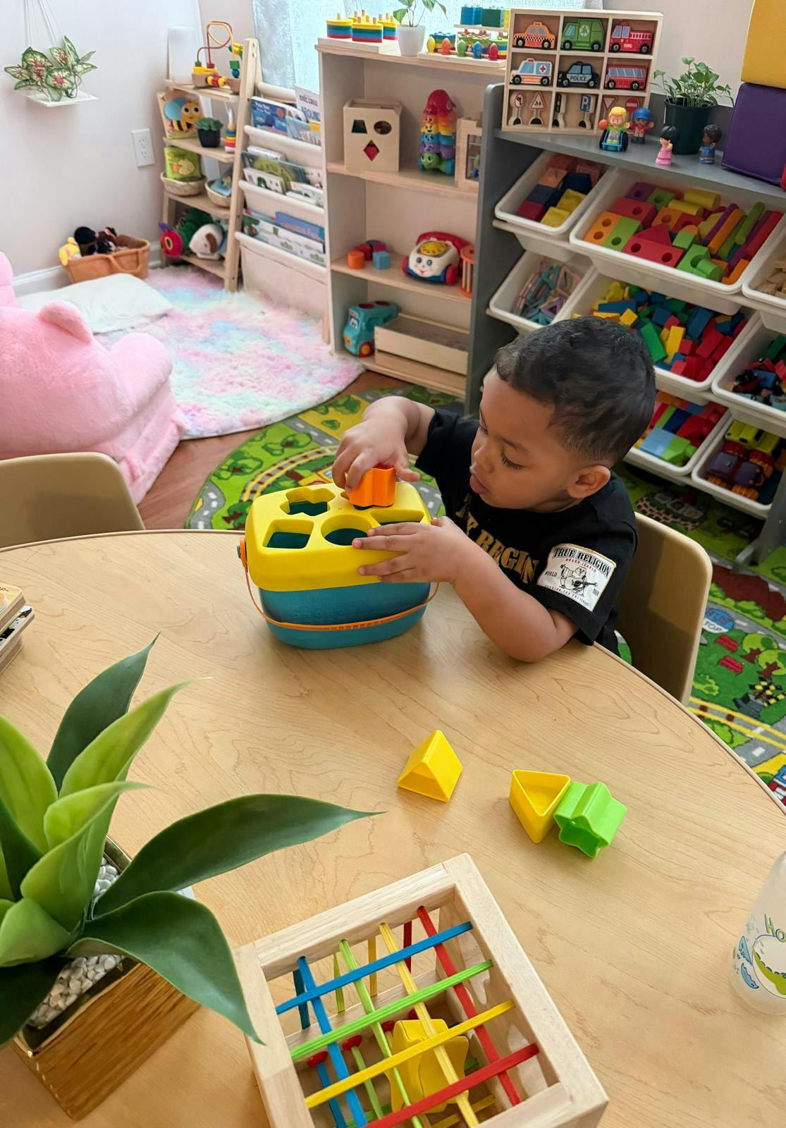 Child playing with a shape sorter in a classroom