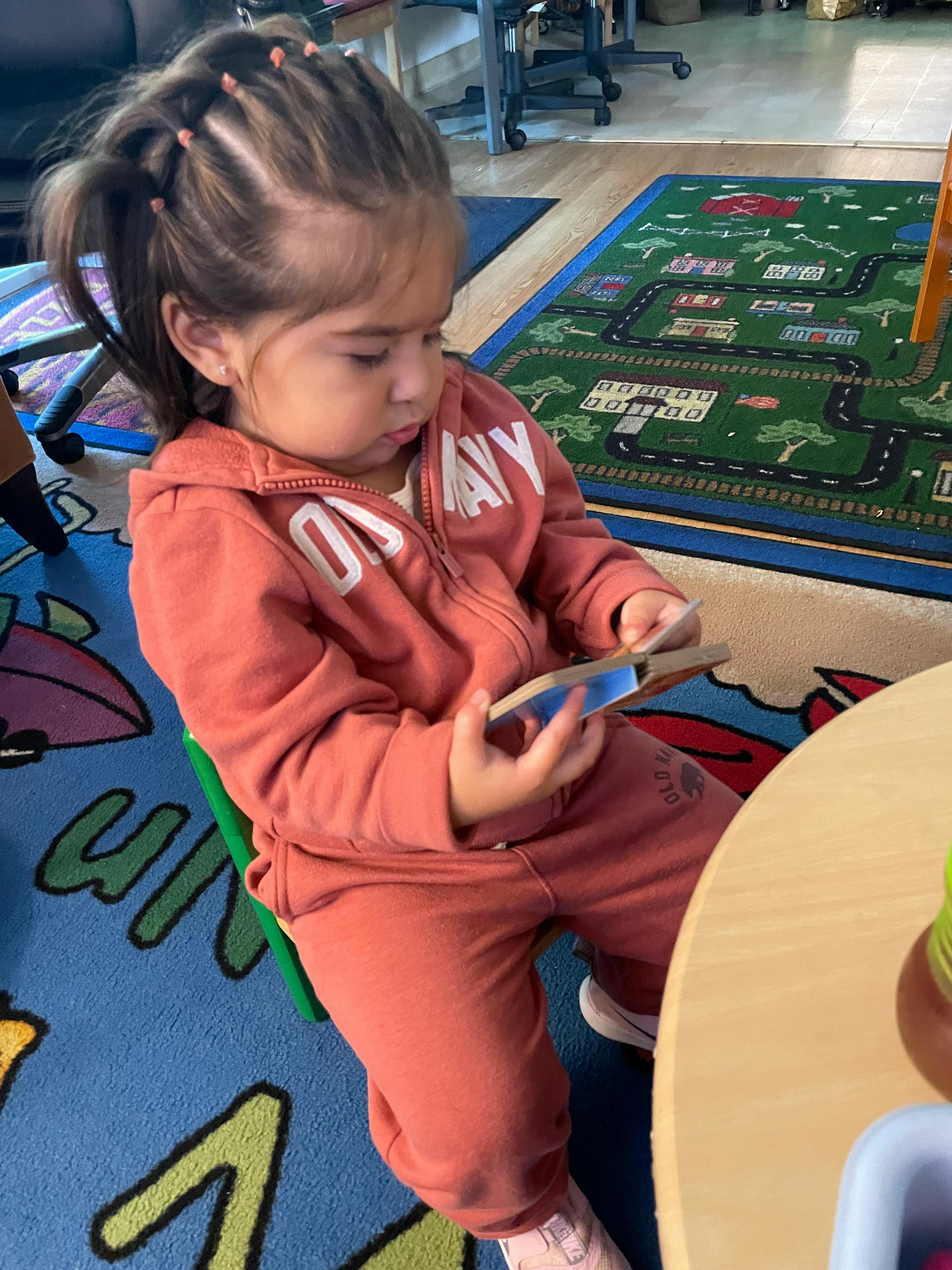 Child sitting on a chair and holding a small book