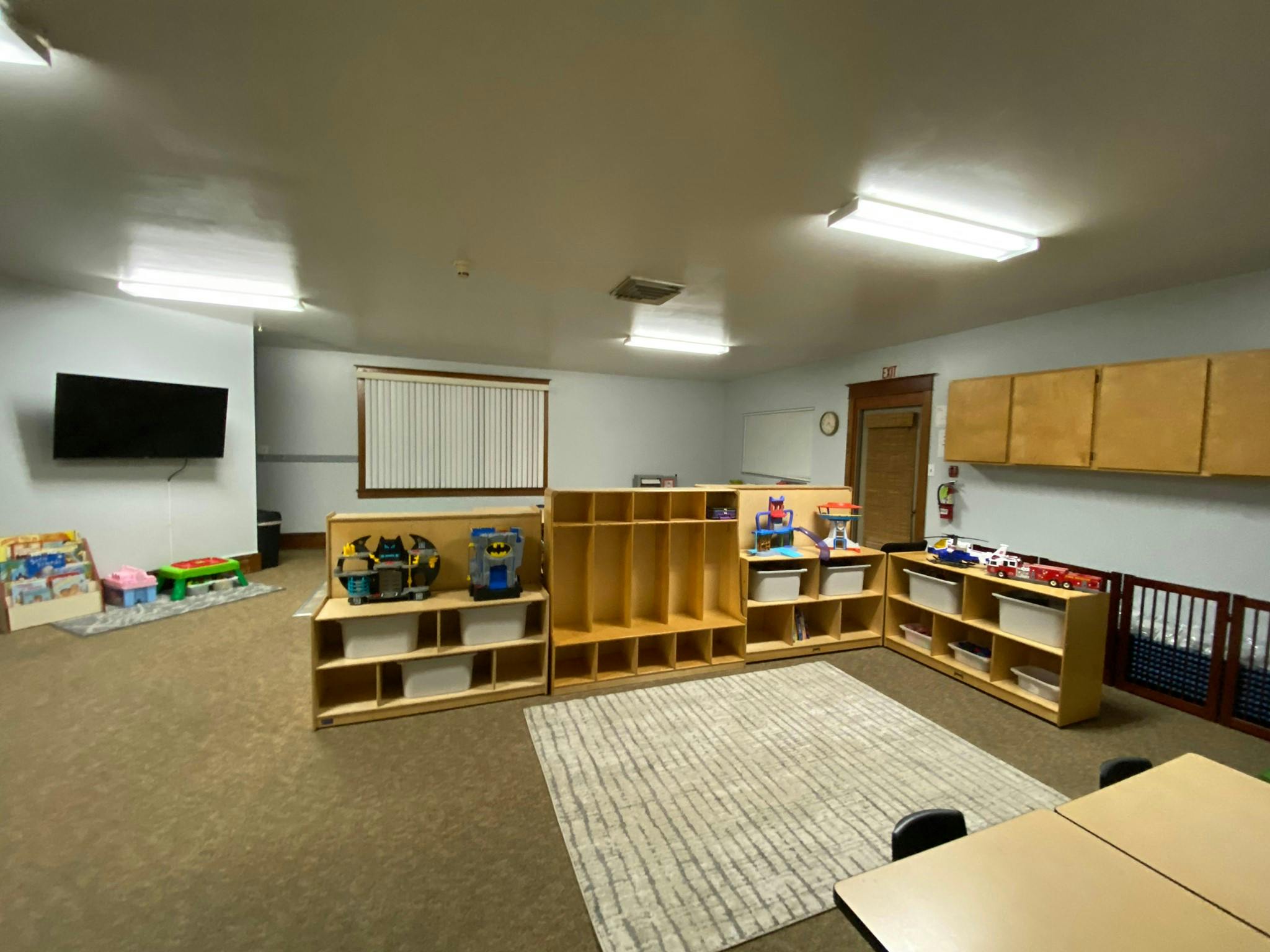 Empty classroom with cubbies, shelves, and a rug