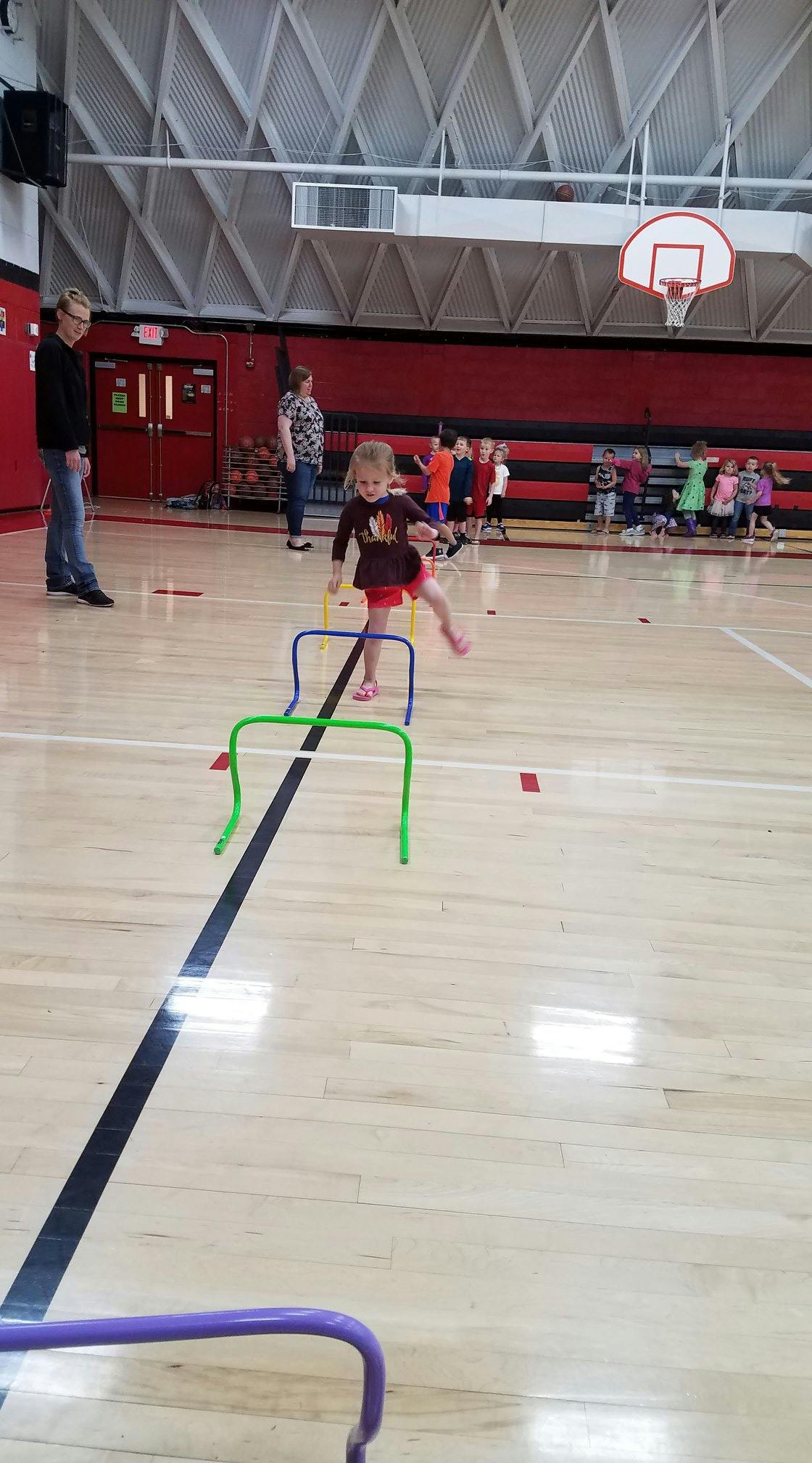 Child stepping over a hurdle in a gymnasium