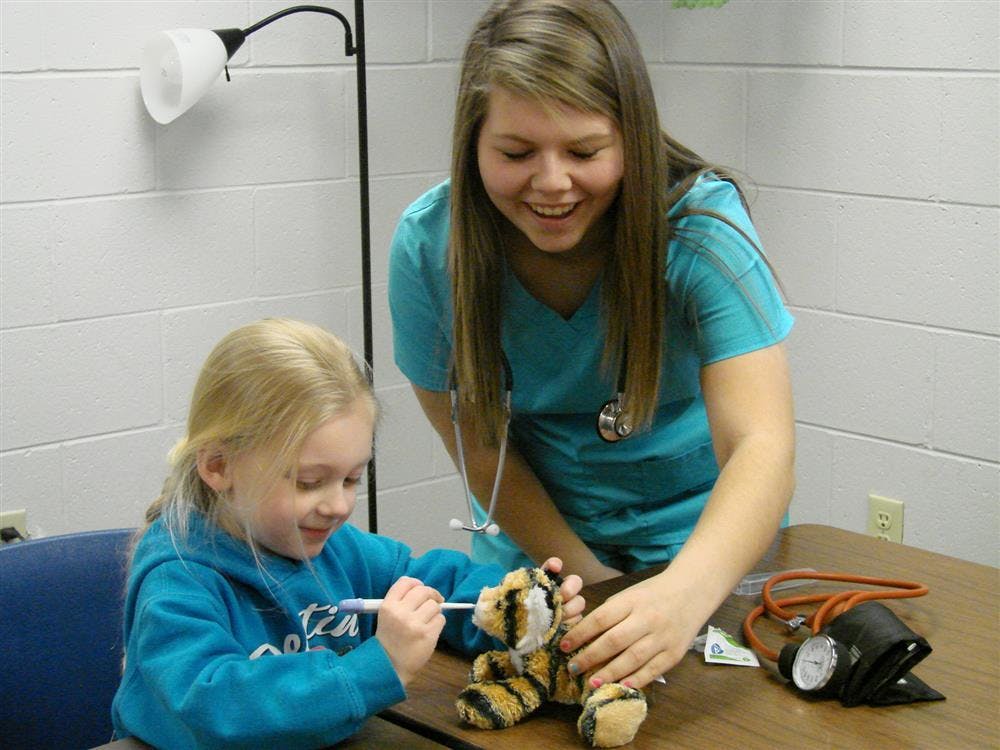 Adult and child playing with a stuffed animal and medical tools