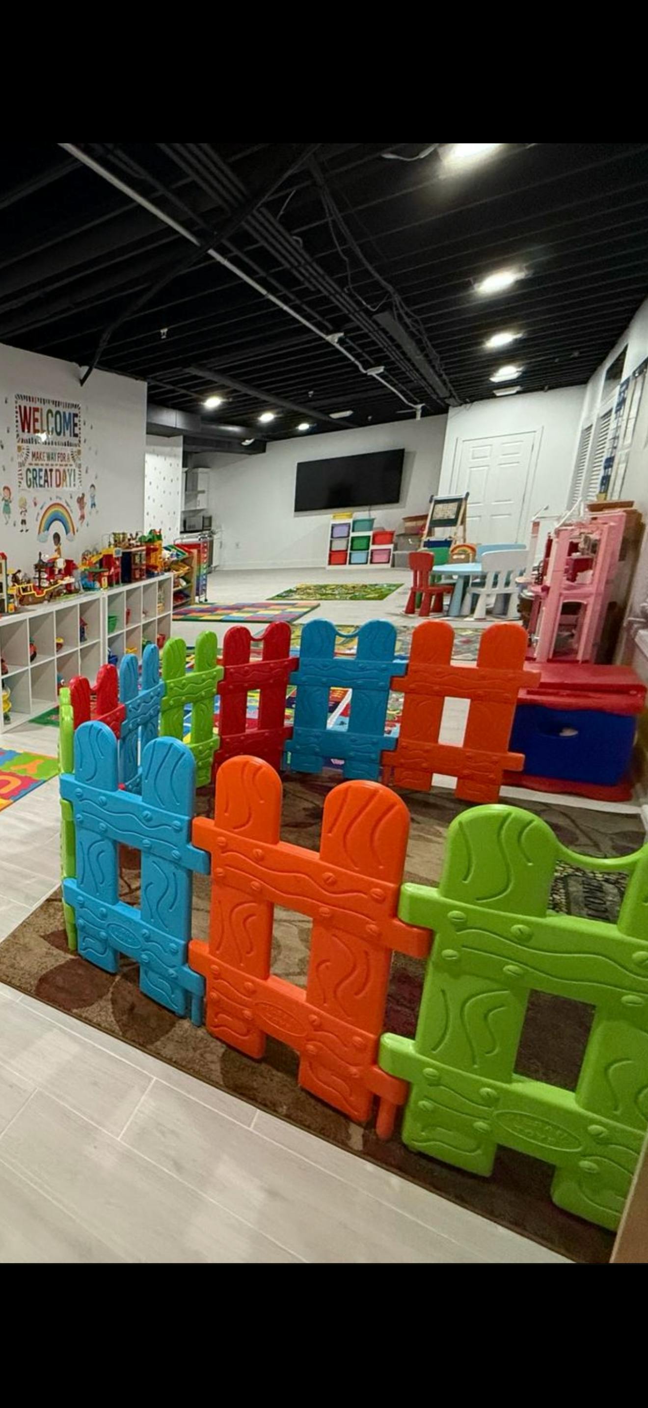 Colorful plastic fence in a children's playroom with toys and a welcome sign