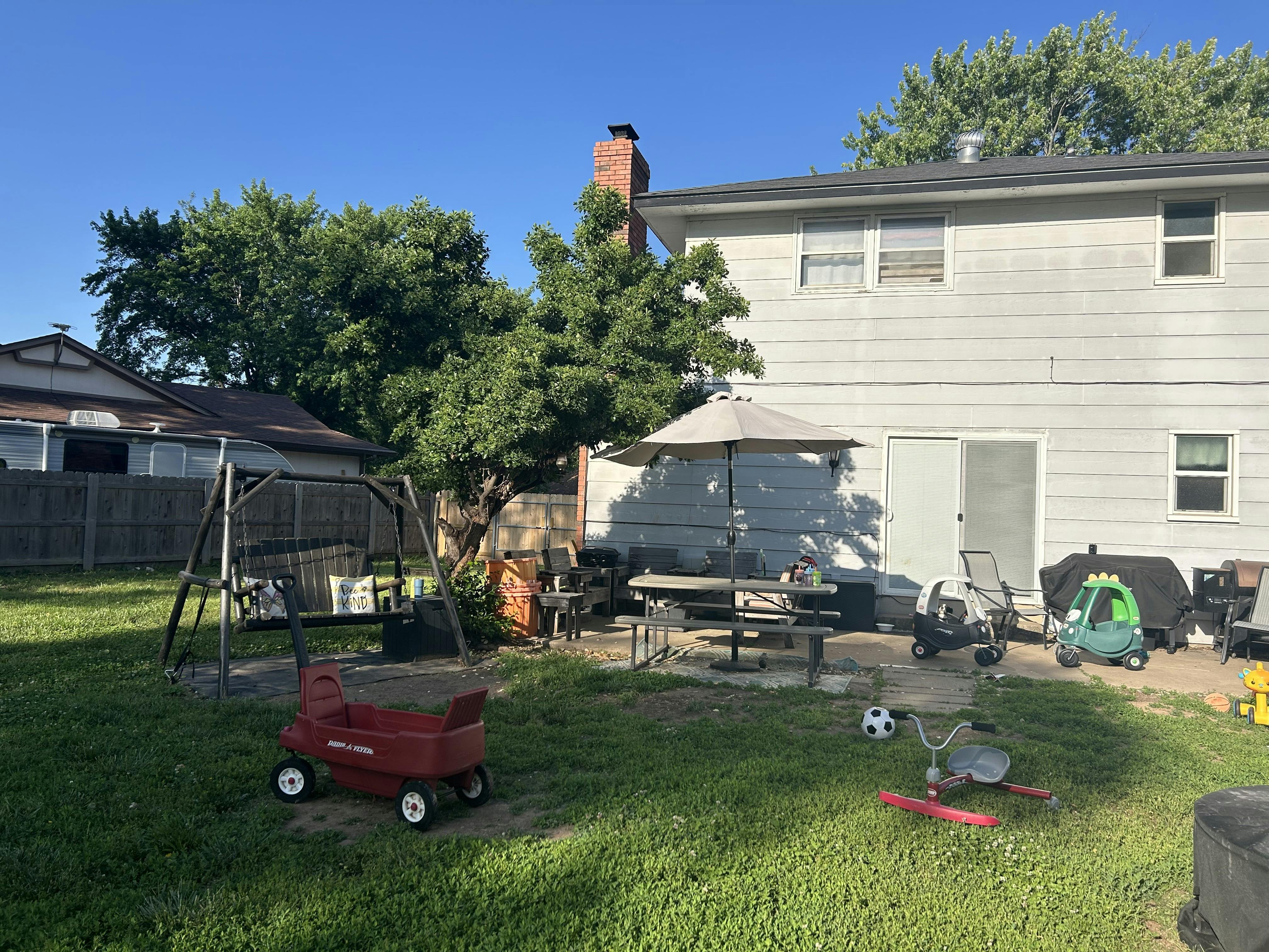 Backyard with a house, patio furniture, and children's toys