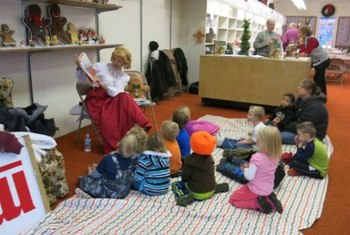 Person reading to a group of children in a room
