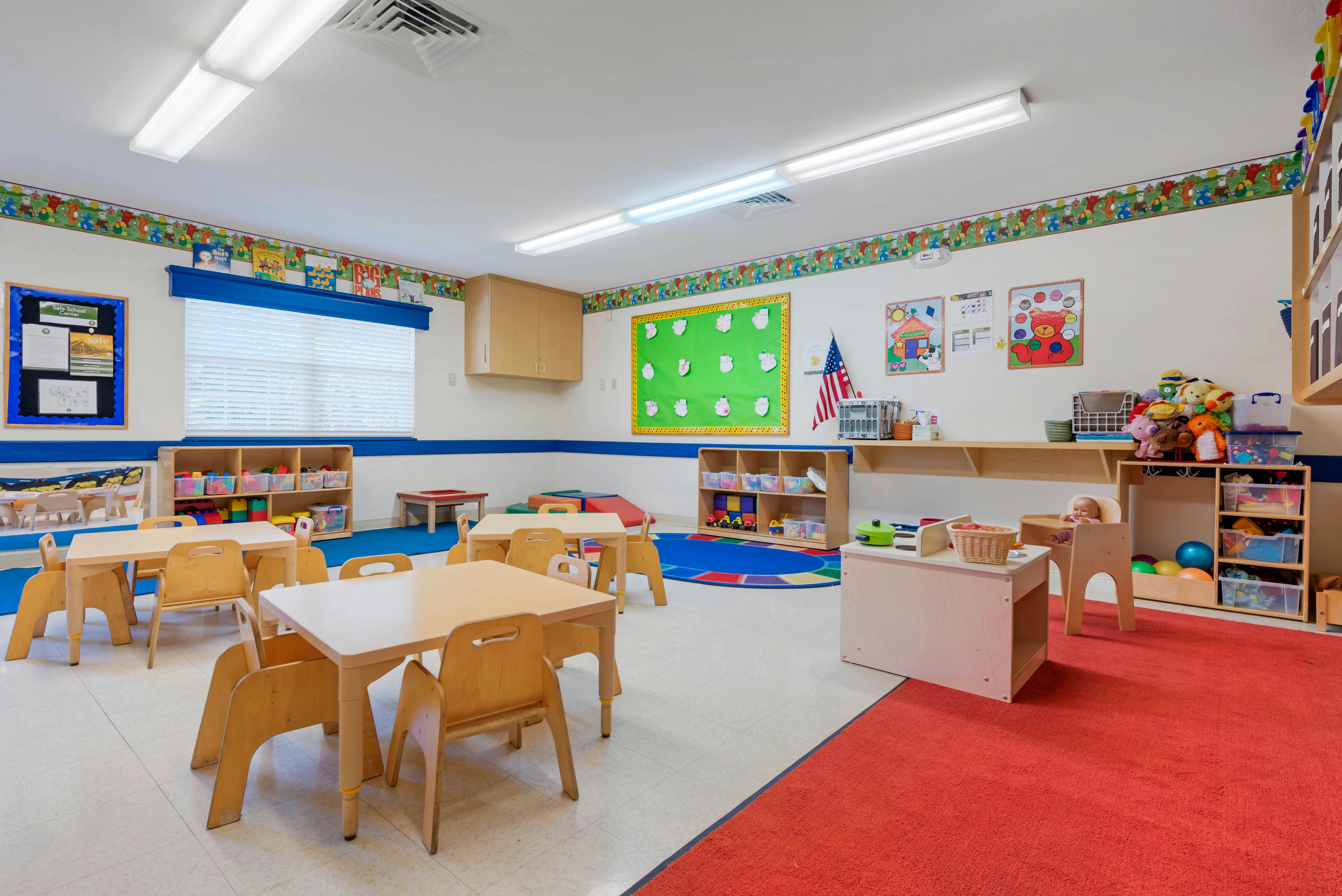Classroom with tables, chairs, colorful rugs, and learning materials