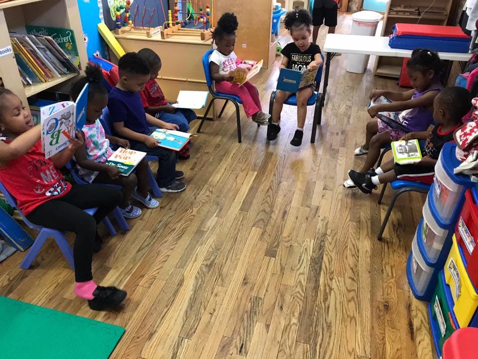 Children sitting in chairs reading books in a classroom