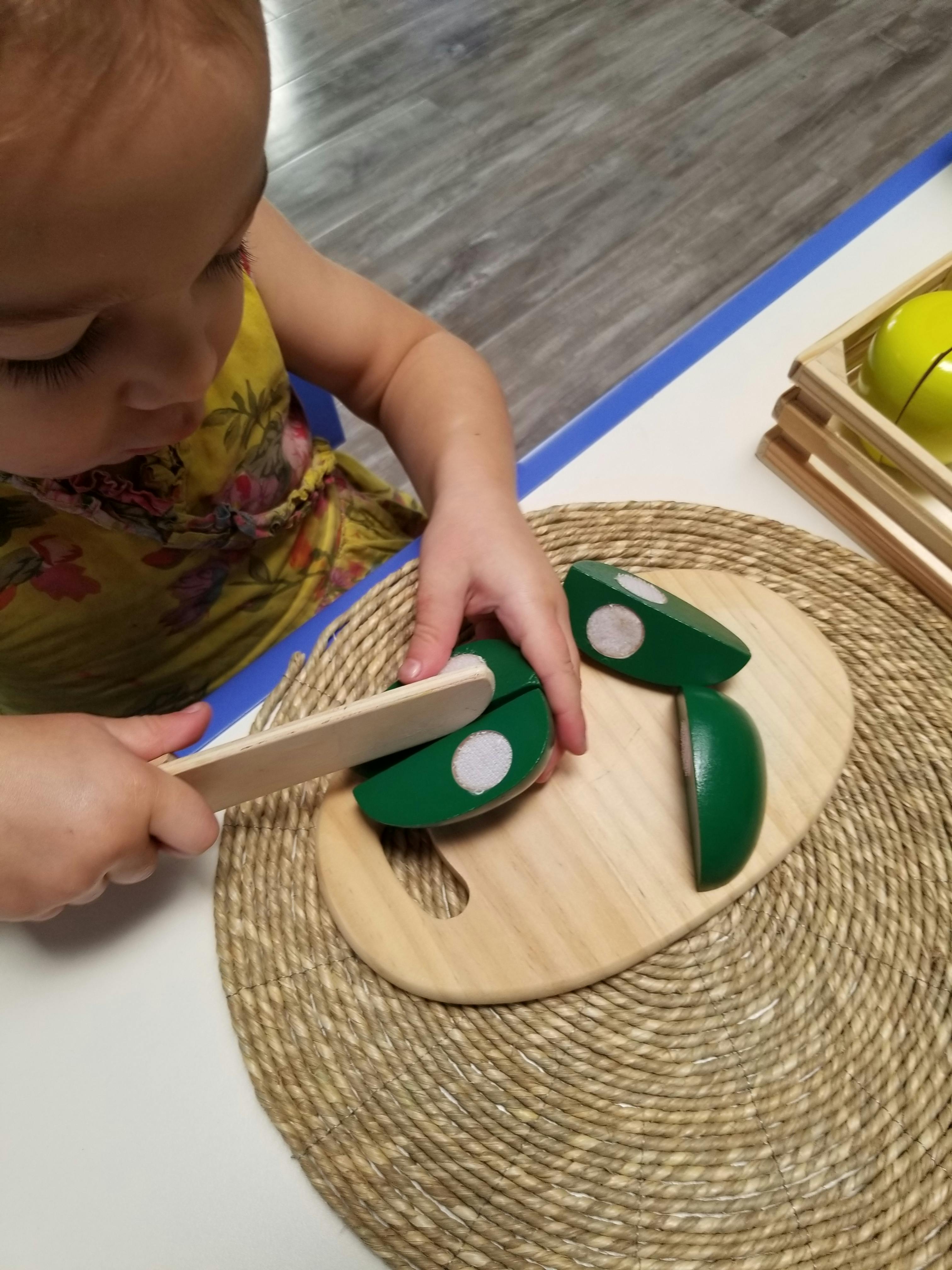 Child playing with toy food and knife on a cutting board
