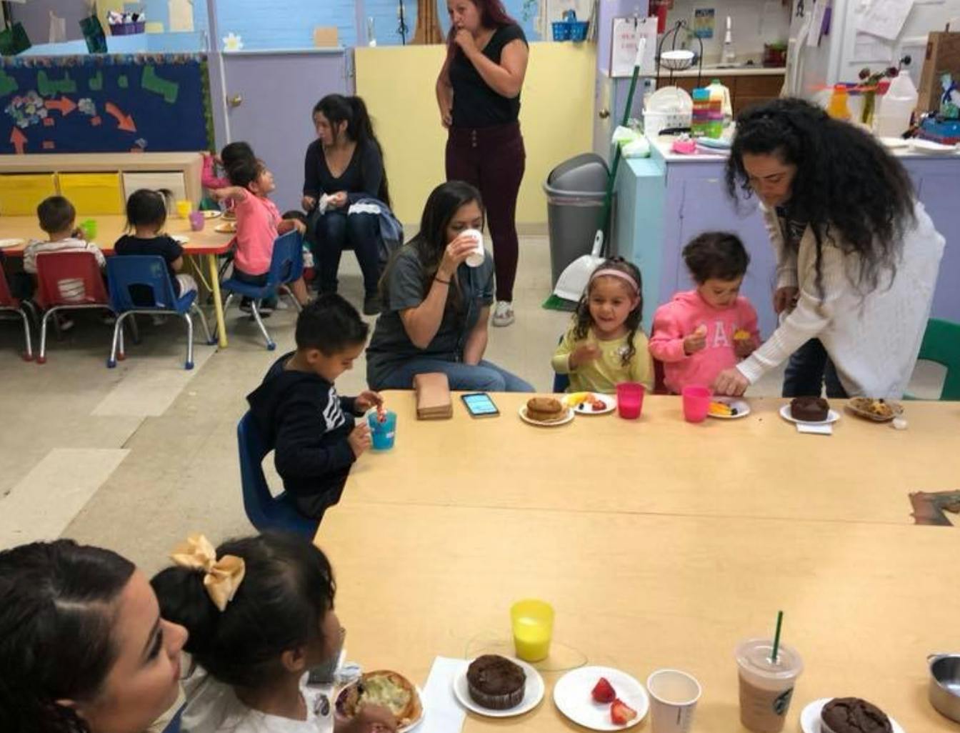 Adults and children sitting at tables eating snacks and drinks