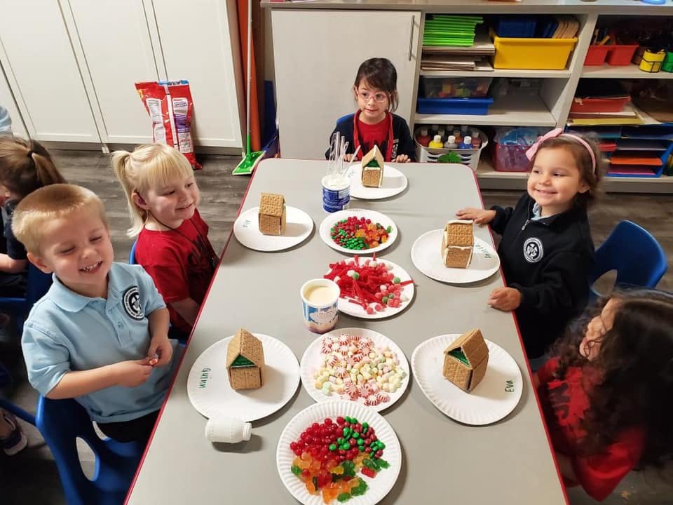 Children decorating gingerbread houses at a table