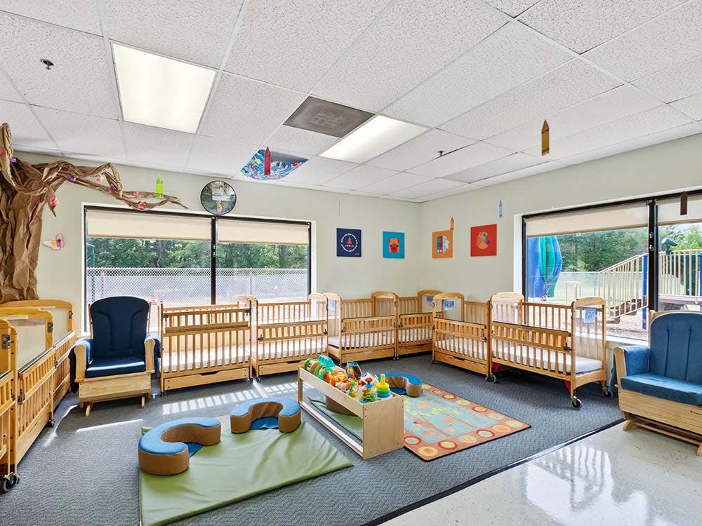 Cribs and small play areas in a daycare nursery room