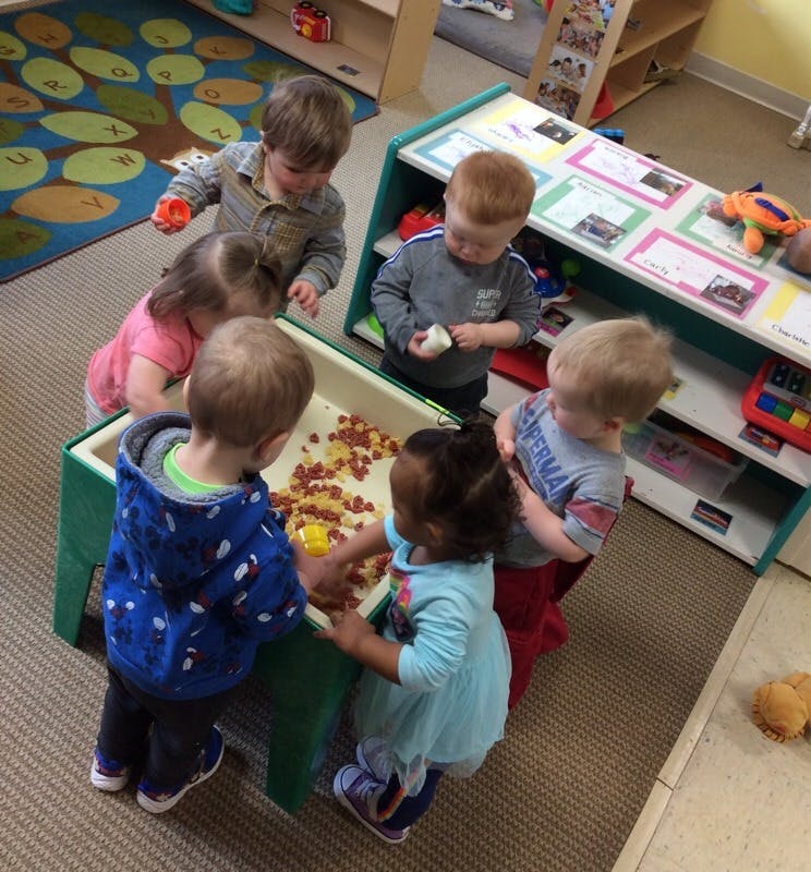 Children playing around a sensory table with cereal