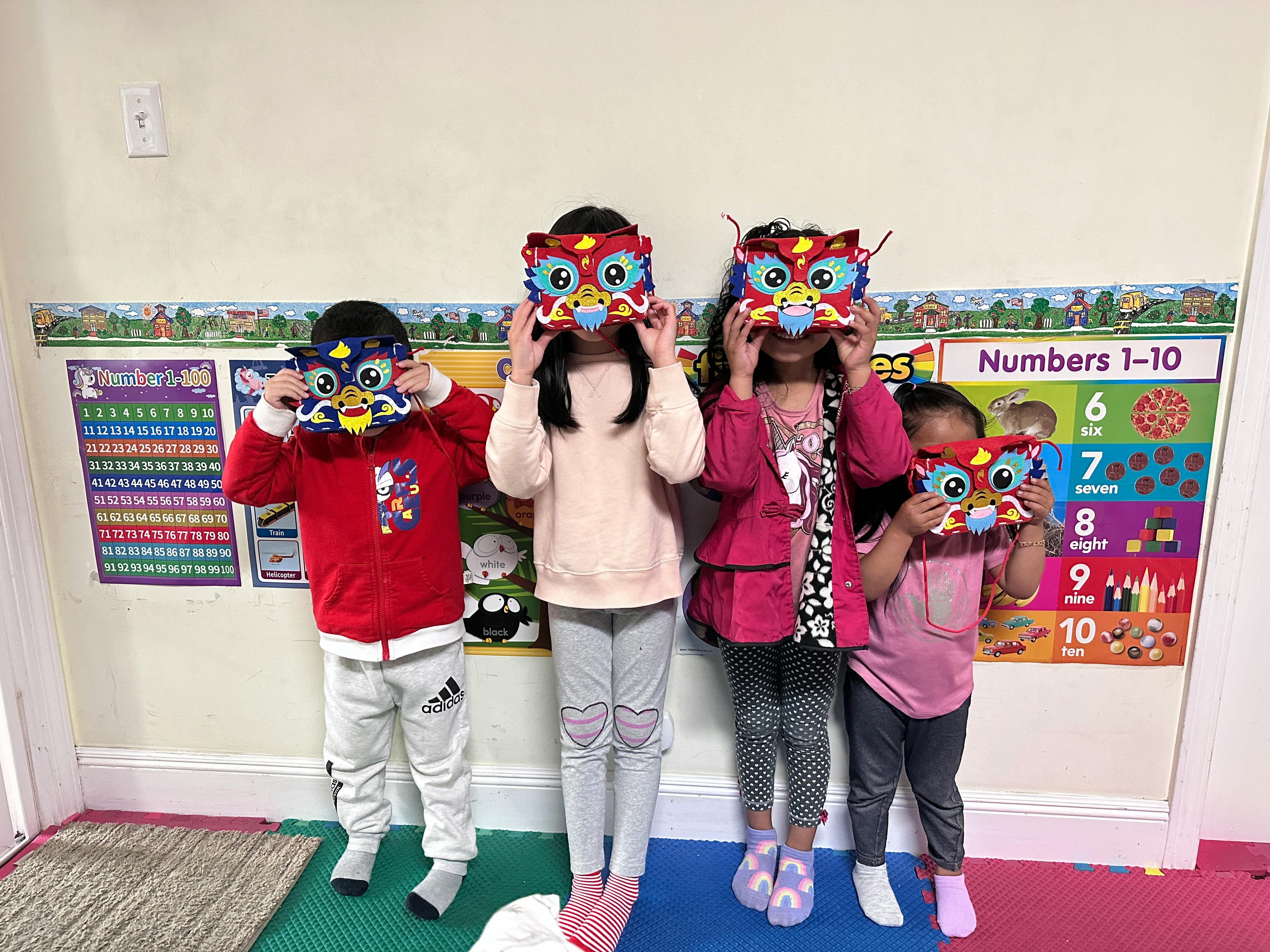 Four children holding up colorful masks to their faces