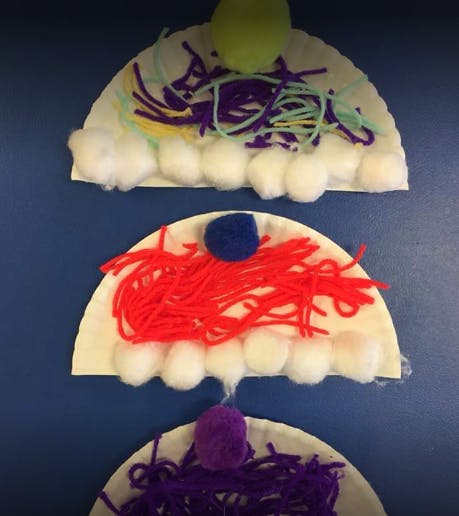 Crafts made from paper plates, yarn, and pom-poms
