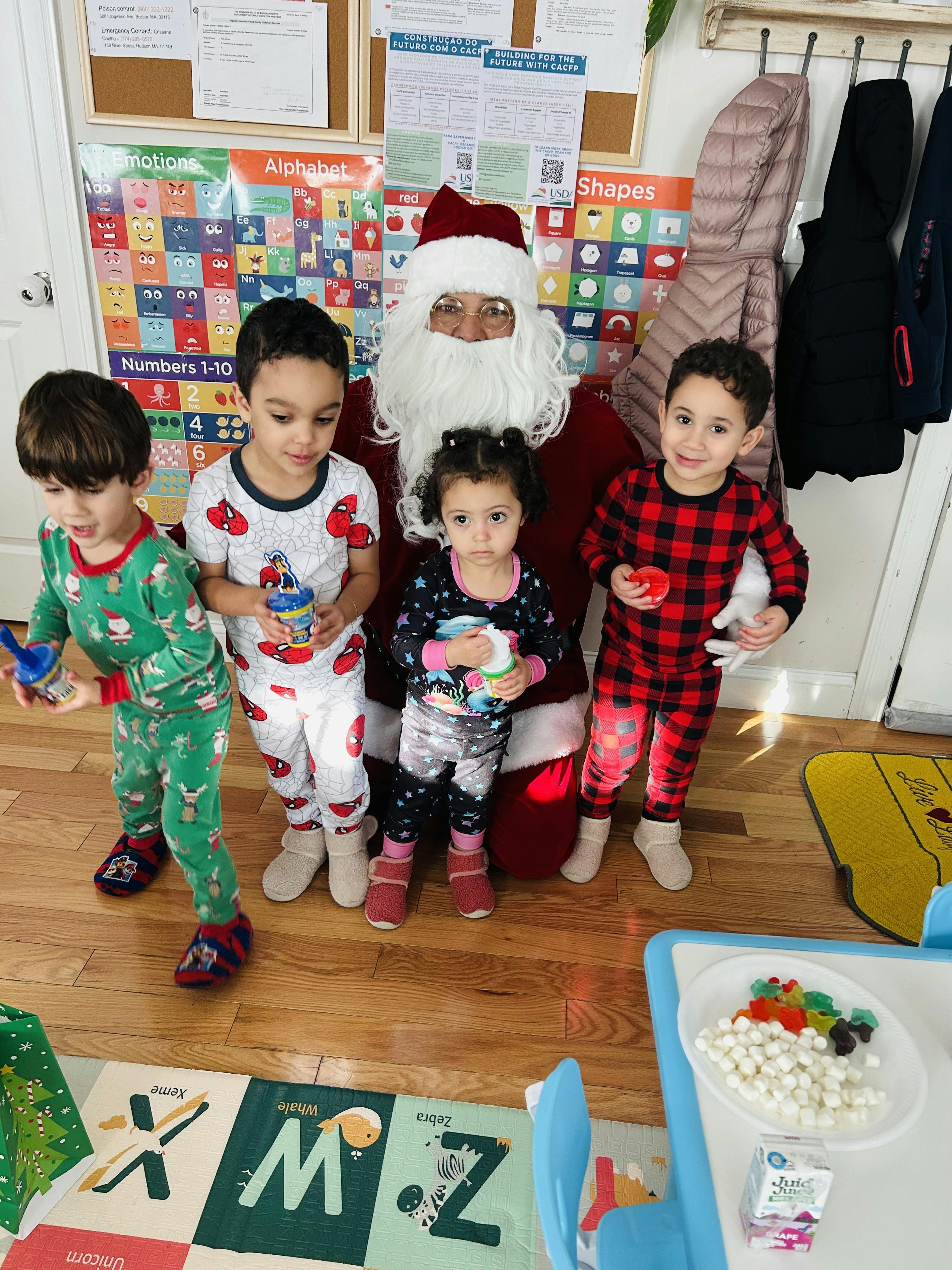 Person dressed as Santa Claus with four children in pajamas