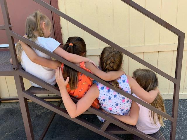 Four children sitting on stairs with arms around each other