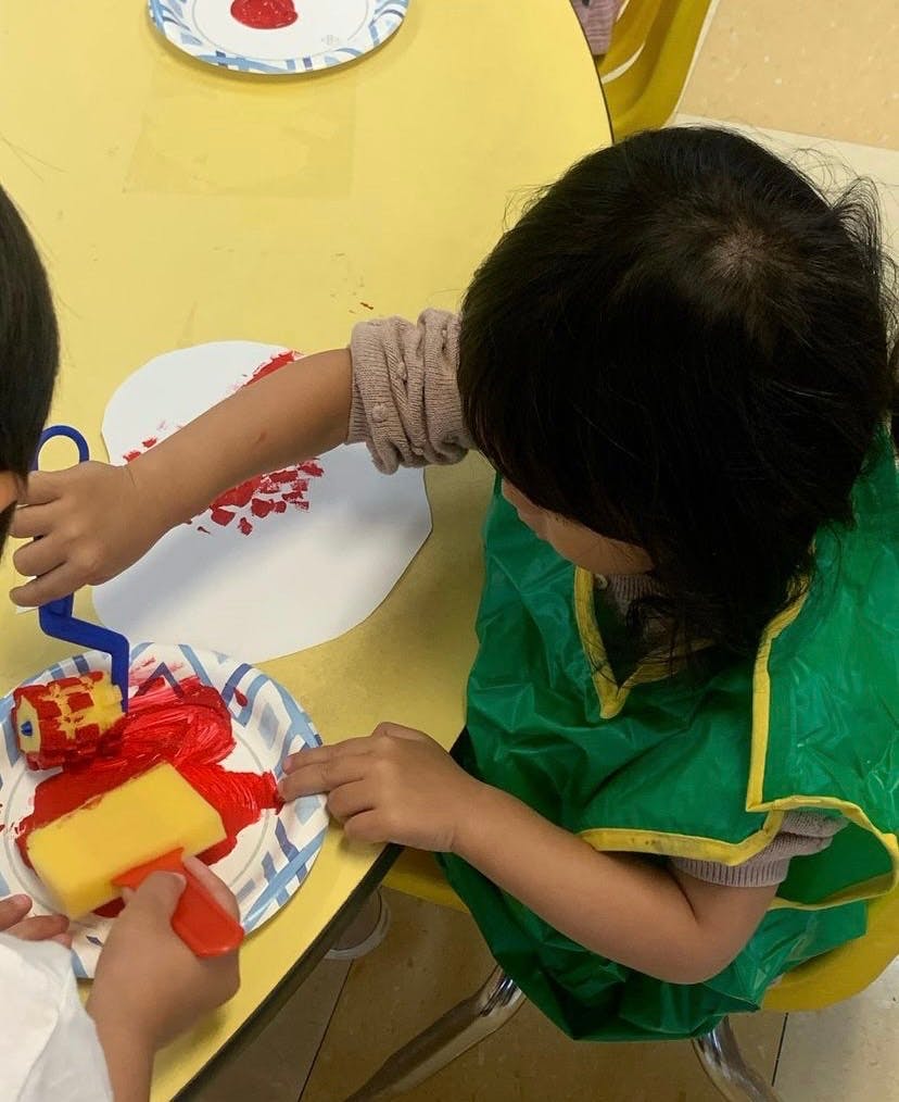 Child painting with a roller and sponge in a classroom