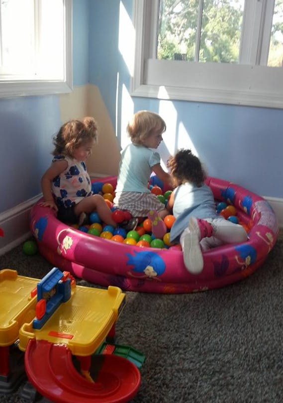 Three children playing in a pink ball pit