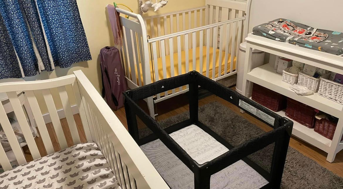 Three cribs in a room with a changing table