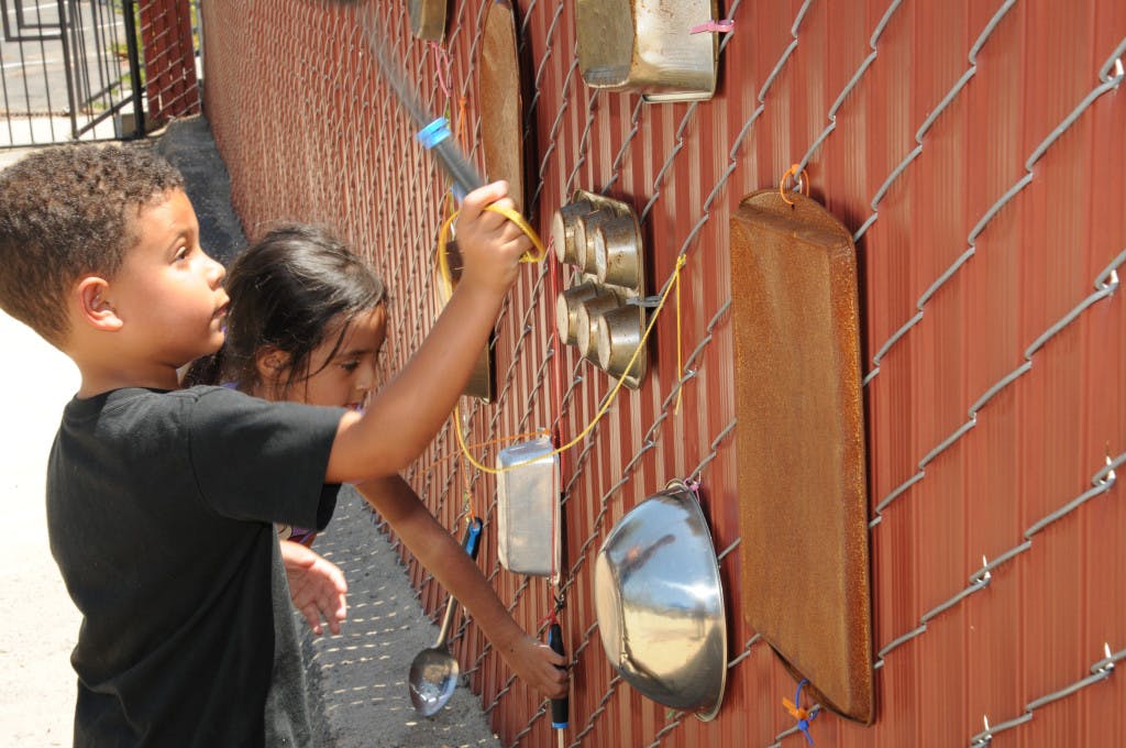 Two children playing with an outdoor music wall