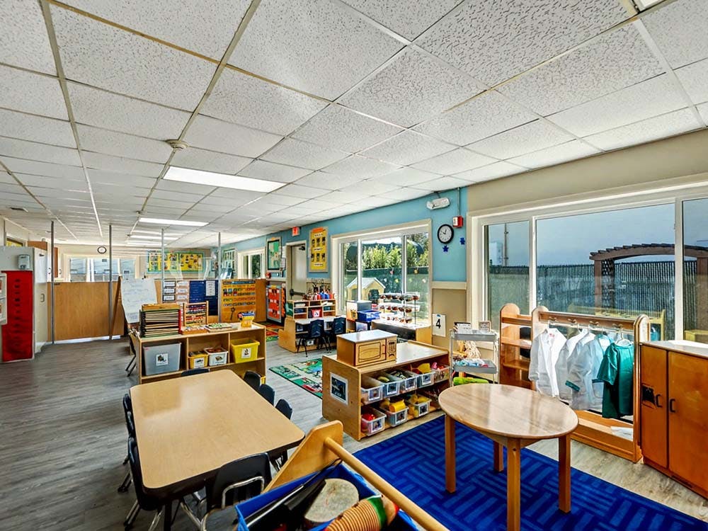 An empty classroom with small tables, chairs, and learning materials