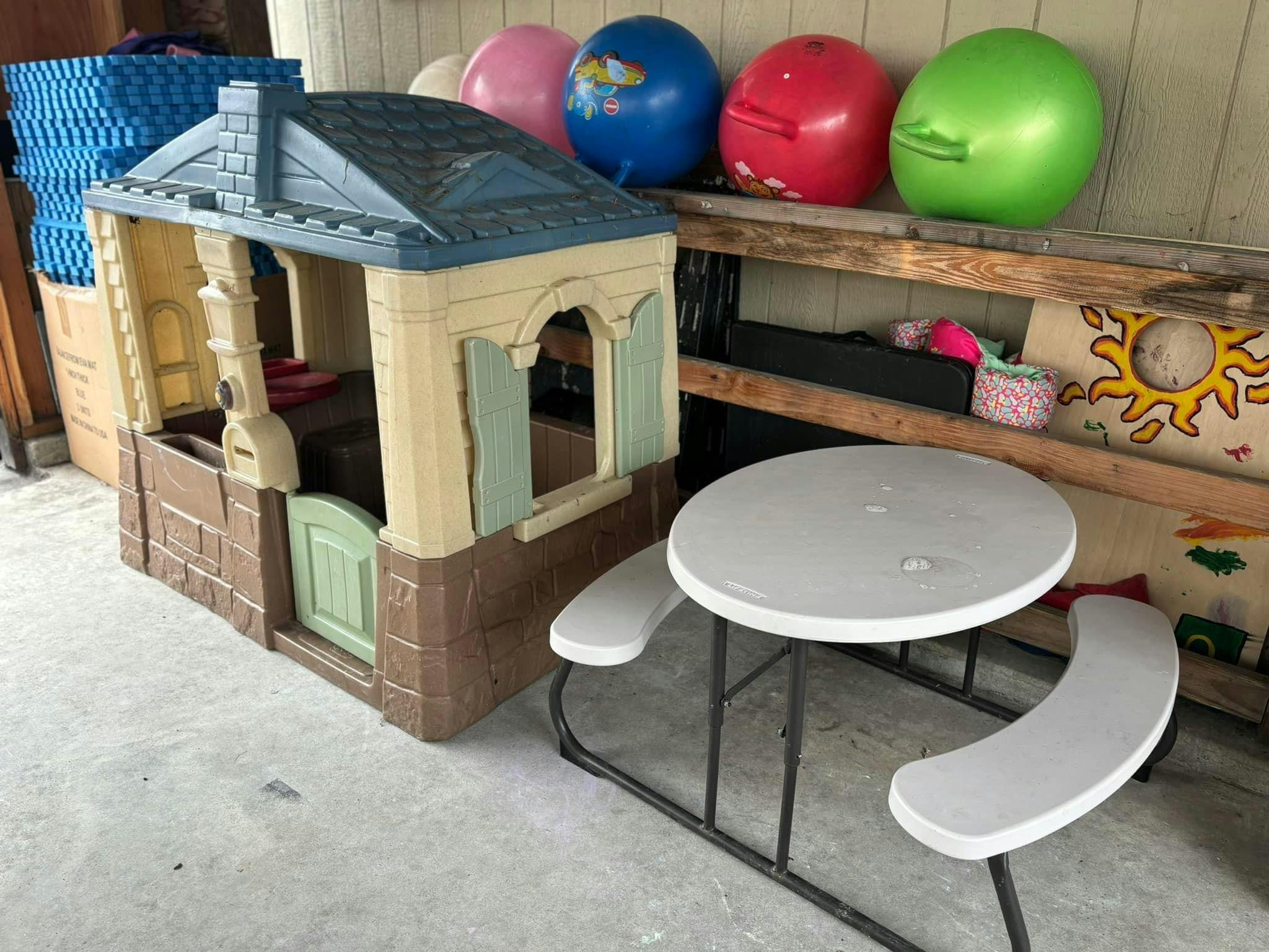 Plastic playhouse and a small round picnic table with attached benches