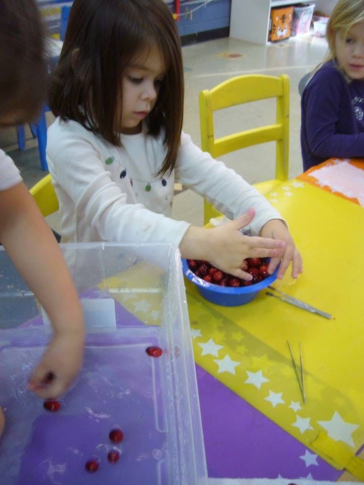 Child playing with berries in a classroom