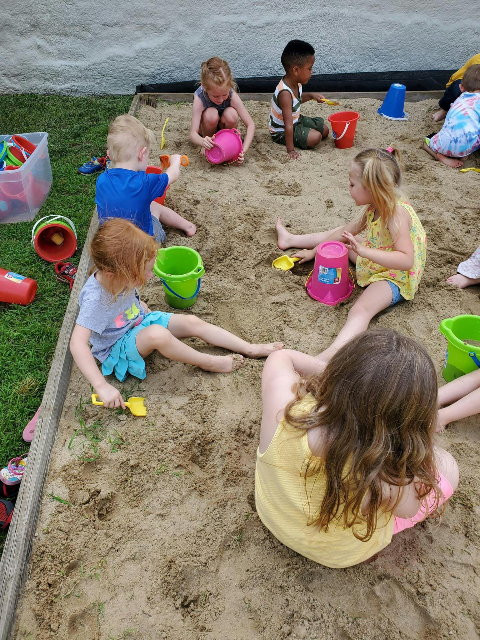 Children playing in a sandbox with buckets and shovels